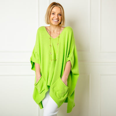 The lime green V Neck Pocket Poncho jumper with a v neckline and ribbed detailing along the bottom hemline